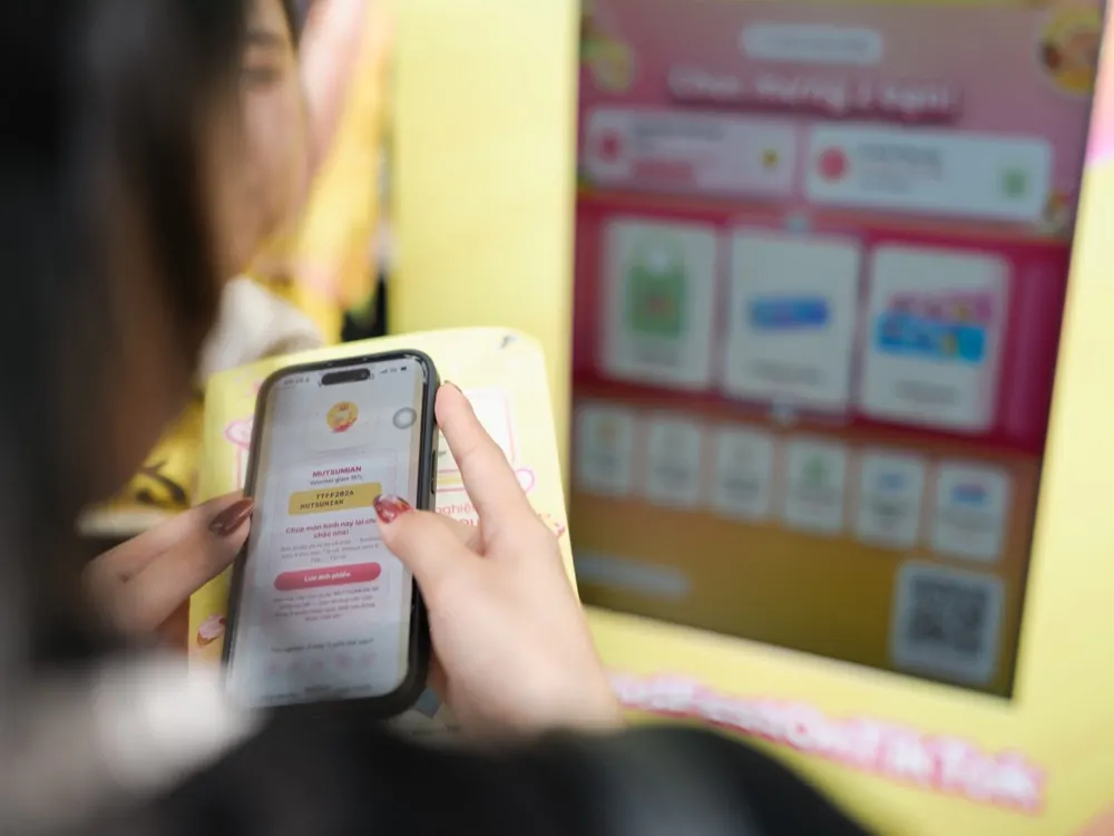 Khách chơi game chọn quà trên điện thoại cạnh máy phát mẫu